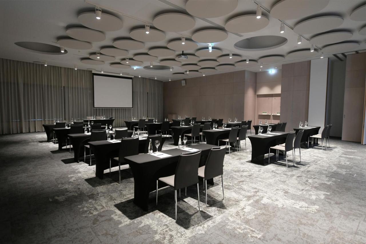 Отель Eurostars Universal Lisboa Экстерьер фото The image shows a spacious conference or meeting room set up for an event. The room features several rectangular tables arranged in a grid formation, each equipped with black chairs. There are glasses and water bottles on the tables, indicating that 