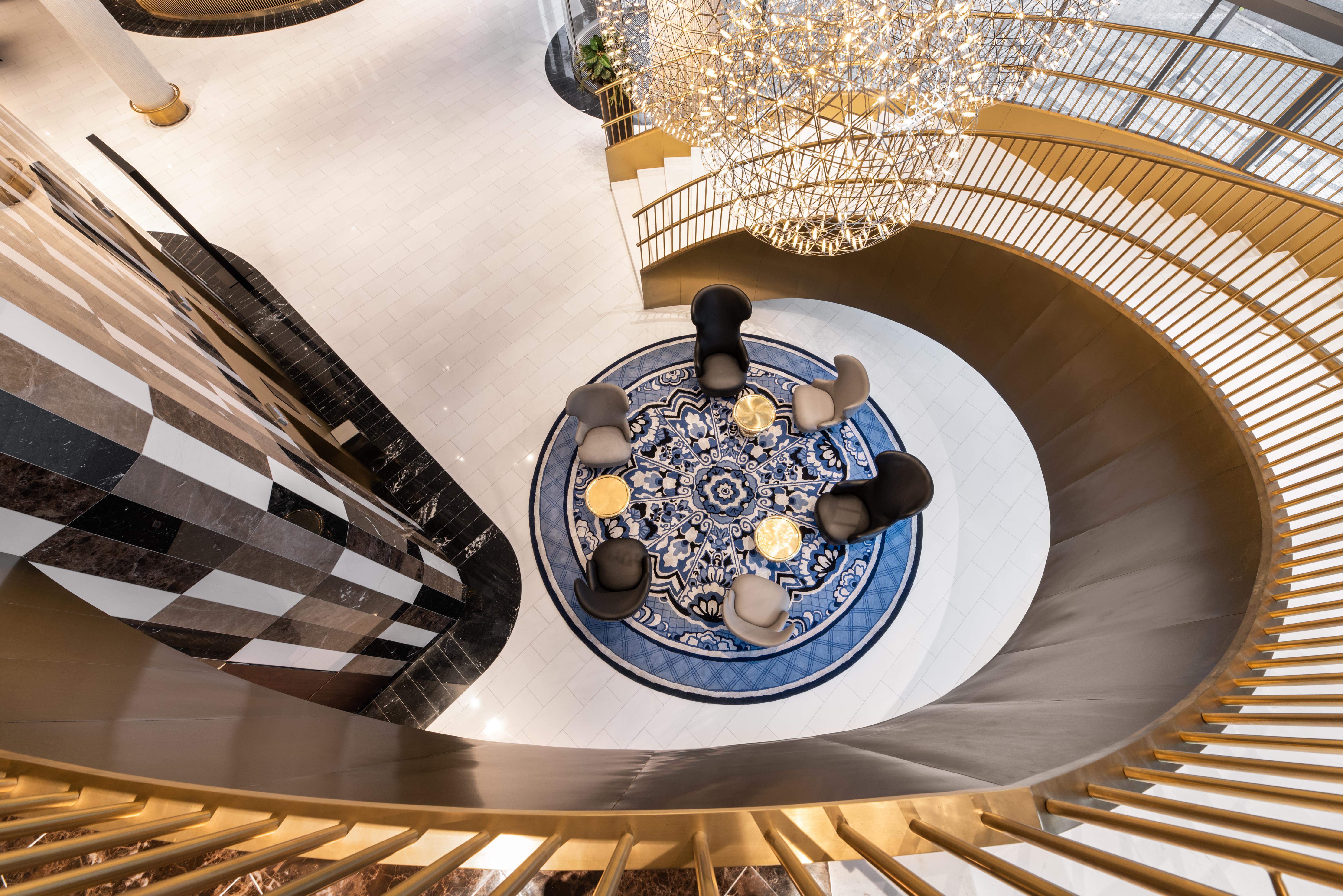 Отель Eurostars Universal Lisboa Экстерьер фото The photo depicts a stylish indoor space featuring a spiral staircase that leads to a circular area with chairs arranged around a decorative rug. The rug has a blue and white pattern, adding a sophisticated touch to the setting. Above the seating are